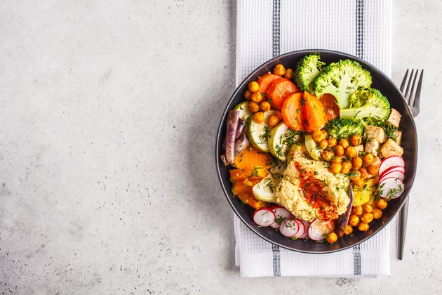 Vegan Buddha bowl with baked vegetables, chickpeas, hummus and tofu, top view.