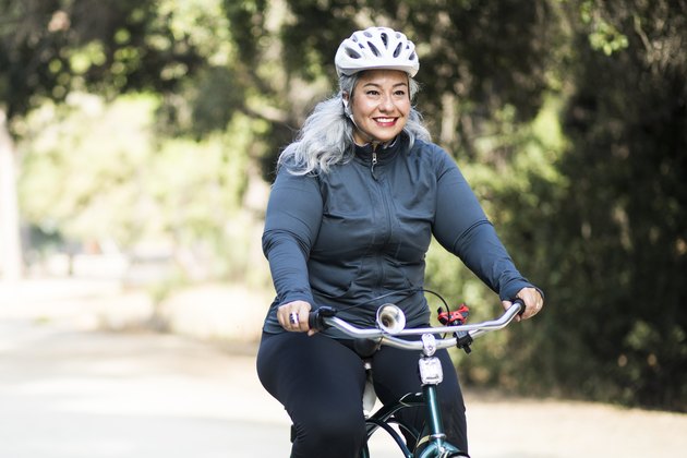 Older woman wearing a helmet and biking outdoors