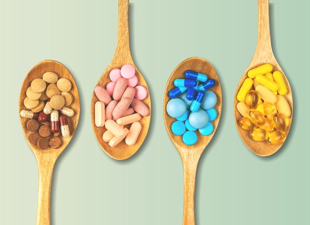 Four wooden spoons filled with multicolored supplement pills