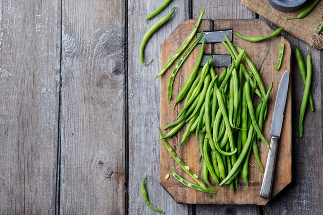 Green beans on wooden cutting board. Top view