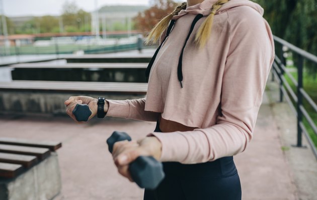 Girl training with dumbbells outdoors