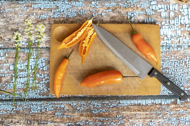 Several ajies being chopped by knife on a kitchen board