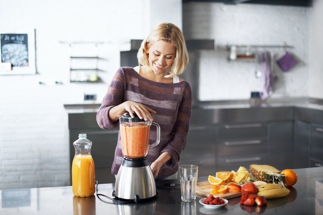 A woman making a fruit smoothie in her kitchen