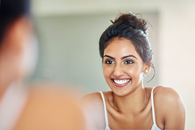 Smiling woman looking at her reflection in the bathroom mirror