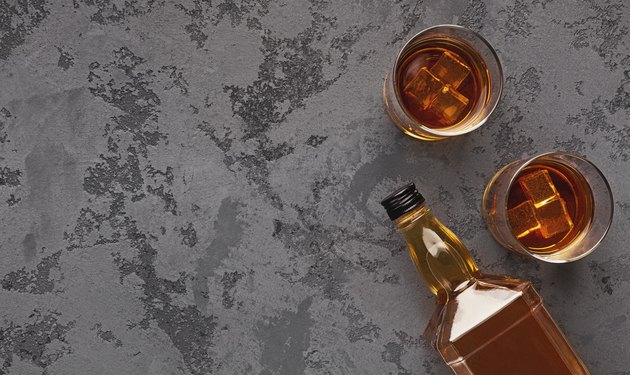 Two glasses of whiskey and bottle aside on marble background