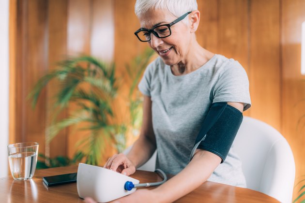An older woman using a blood pressure app to monitor her blood pressure at home