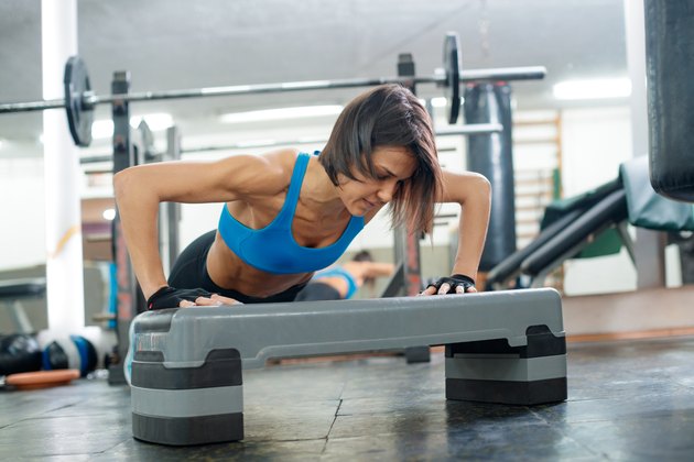 Woman using fitness stepper for push-ups