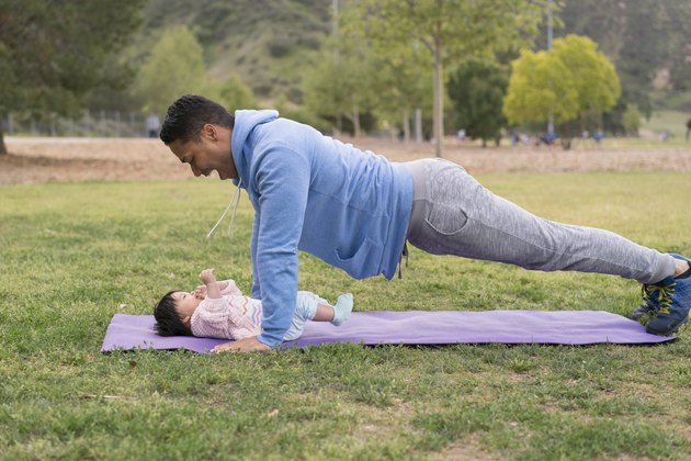 爸爸和宝宝一起在公园里锻炼，享受强壮的身体带来的好处