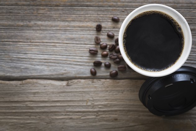Overhead view of cup of coffee and coffee beans on wood