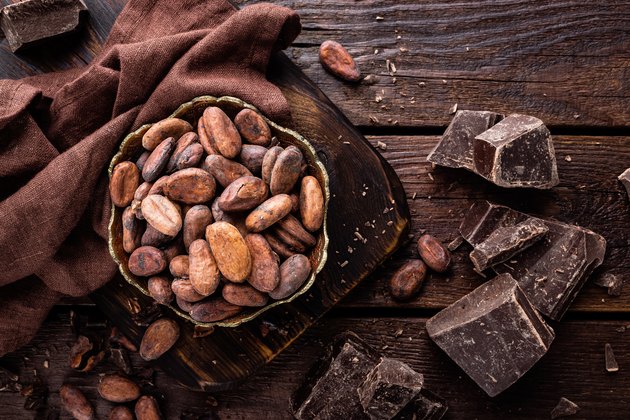 Cocoa beans and chocolate on wooden background