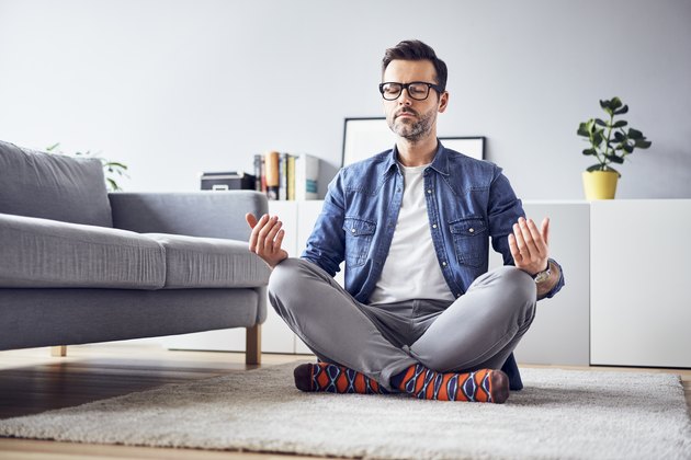 Relaxed man meditating at home in a cross-legged position