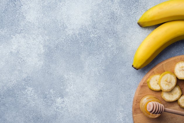 Banana and sliced banana into pieces with honey on textured background, copy space.