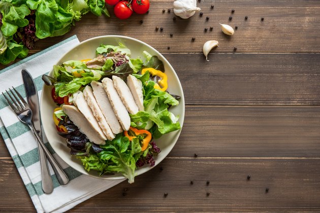 Healthy fresh vegetable salad with skinless boiled chicken breast, top view