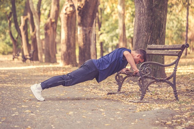 Young sporty man doing push-ups outdoors for chest muscles