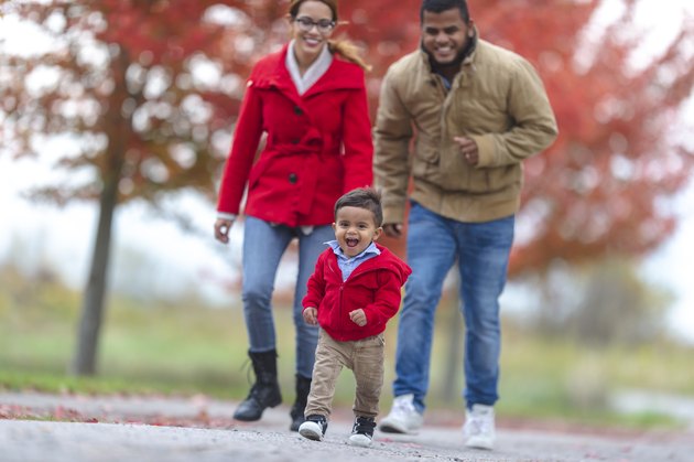 Baby walking outside with parents