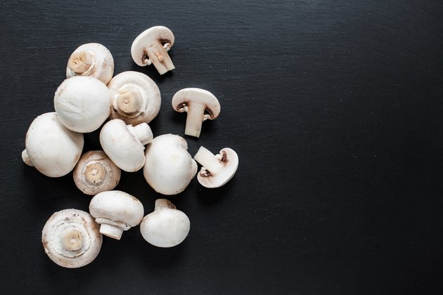 Fresh Mushroom champignon on dark background, sliced and whole with copy space, ready for cooking