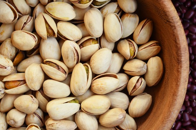 A wooden bowl full of pistachios