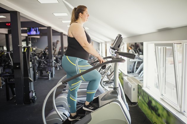 Woman using stepmill for HIIT workout at gym.