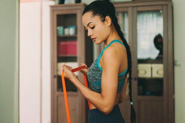 Woman performing resistance band biceps curls.