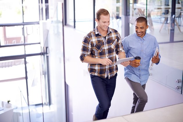 Two male colleagues taking a break from sitting at work by having a walking meeting