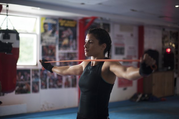 boxer doing resistance band back exercise pull-apart in boxing gym
