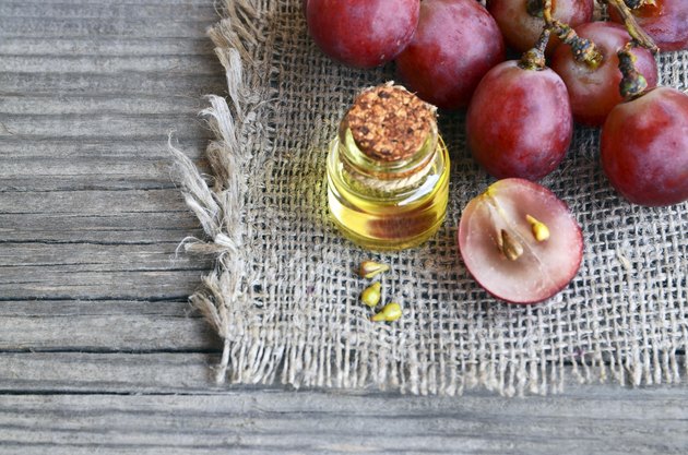 Bottle of organic grape seed oil for spa and bodycare and fresh ripe grapes berries on old wooden table.Healthy food,Bio,Eco products concept.