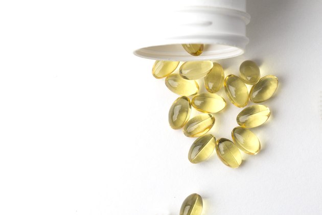 Vitamin D gel capsules. Vitamin D bottle with spilled contents isolated