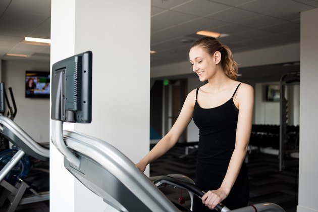 Woman turning on treadmill before workout