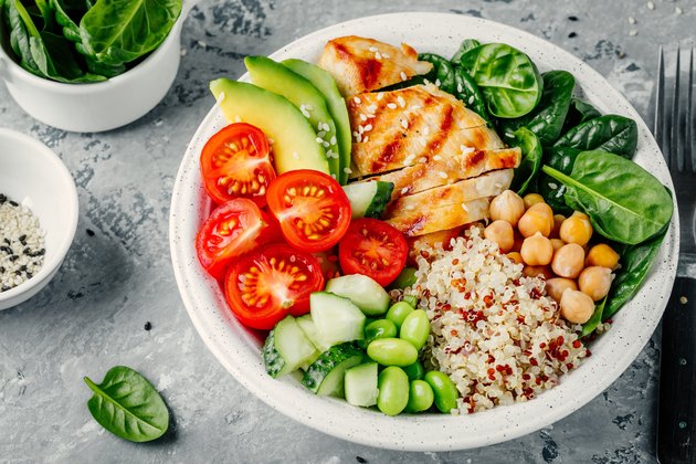 Buddha bowl with spinach salad, quinoa, chickpeas, grilled chicken, avocado, tomatoes, cucumbers, sesame seeds.