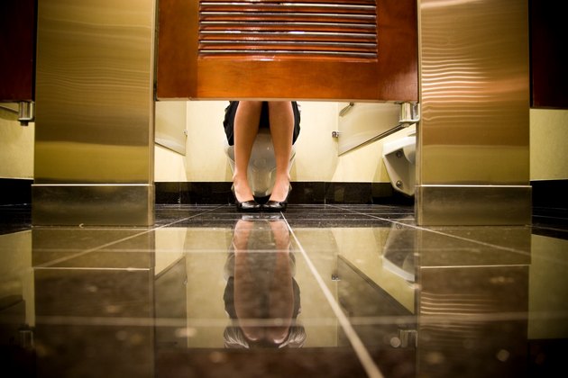 woman sitting on toilet in public restroom