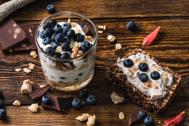 健康早餐冻糕在玻璃杯与蓝莓和吐司在一边，顶部白色涂抹和蓝莓