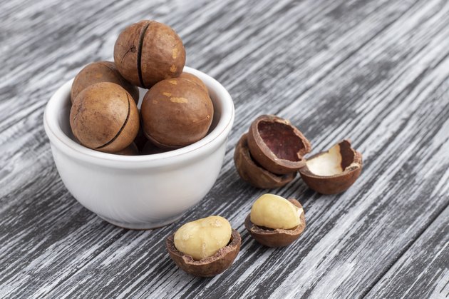 Macadamia nuts in bowl on wooden table.