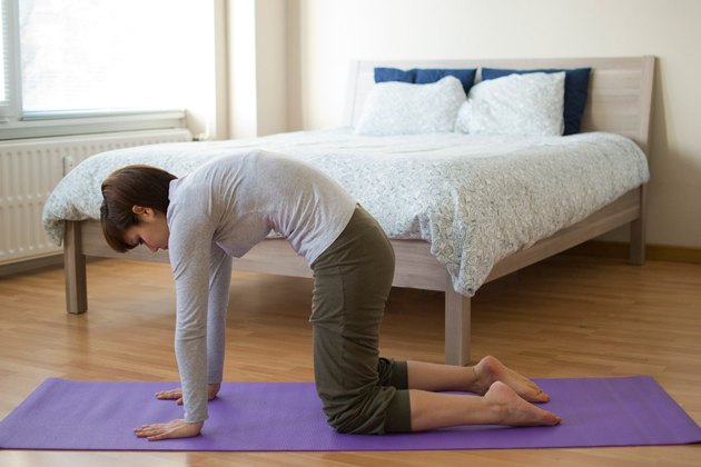 Woman demonstrating how to do Cat-Cow yoga pose for sleep