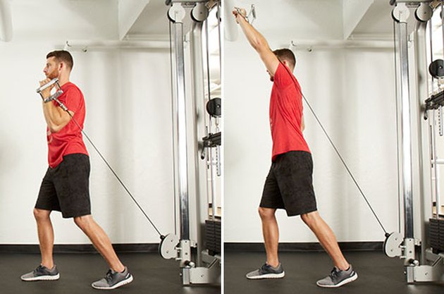 Man performing split-stance single-arm shoulder press on the cable machine