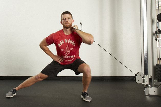 Man doing a side lunge with the cable machine at the gym