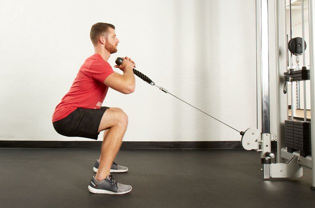 Man performing cable front squat on the cable machine