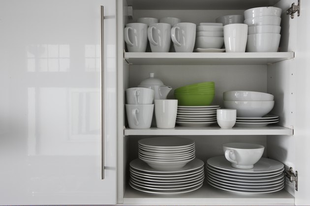 white crockery stacked in cupboard with green bowl