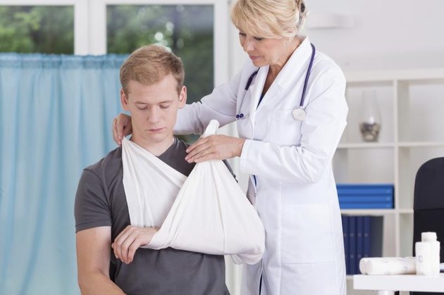 Doctor putting a sling on a boy