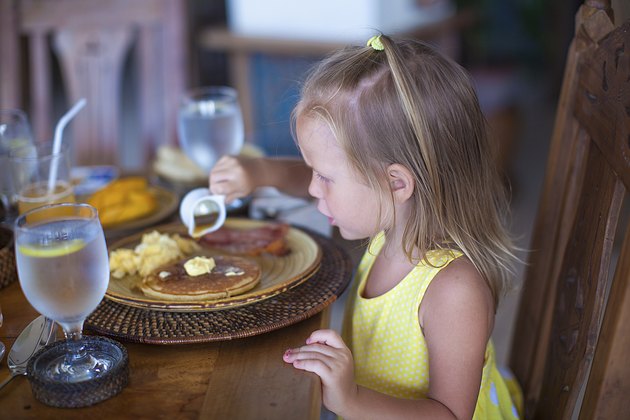 Adorable little girl having breakfast at resort restaurant
