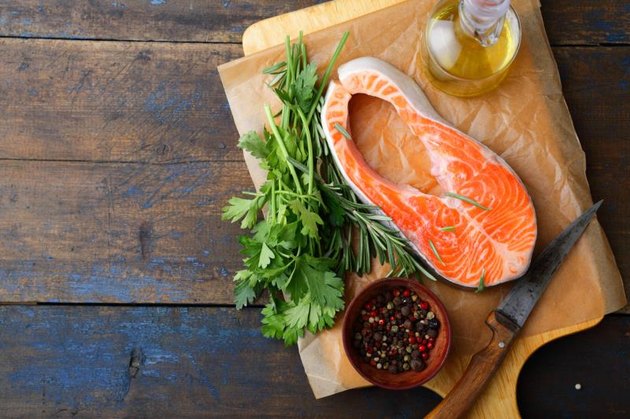 Raw Steak Salmon, parsley, rosemary and spice on a cutting board. Top view
