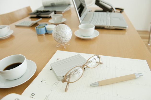 Office with on diary, glasses and coffee cup on desk