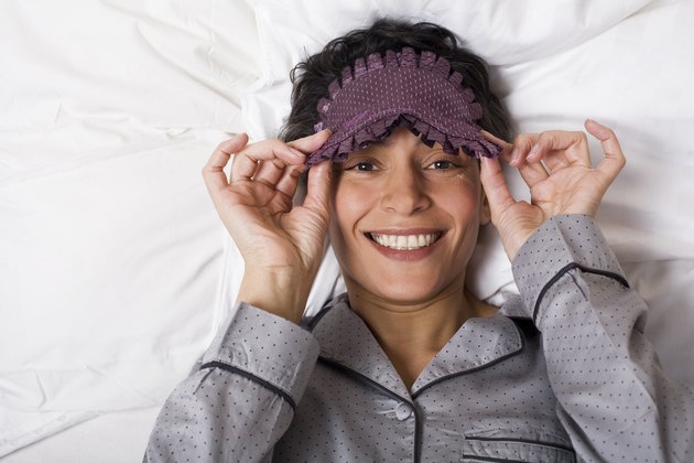 Woman lies with sleeping mask in the bed