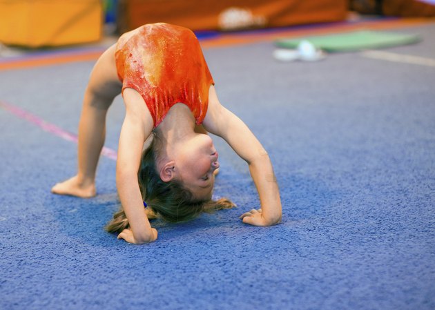 Toddler girl in leotard doing a bridge