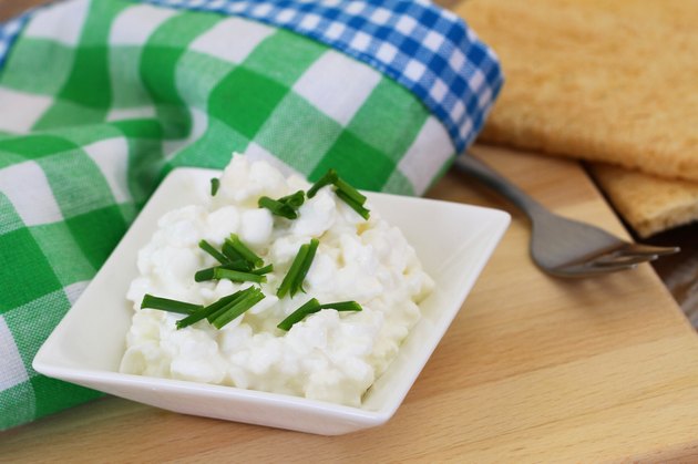 Cottage cheese in white bowl with chives and crisp bread