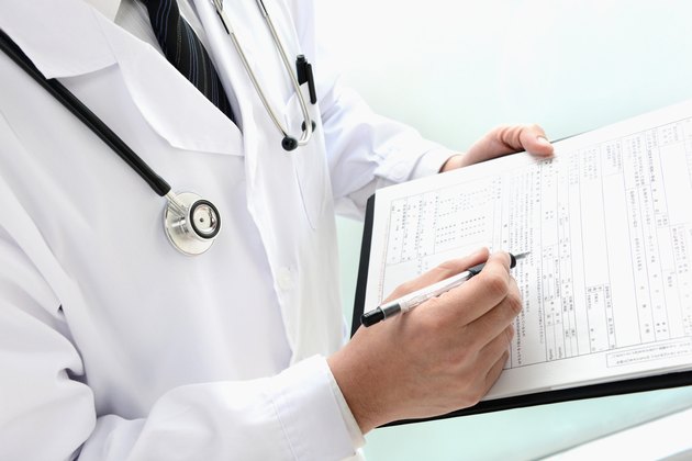 Doctor writing on medical record