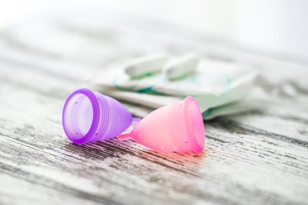 Different types of feminine hygiene products - menstrual cups, sanitary pads and tampons. Selective focus and shallow DOF