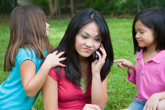 Young woman with cell phone and annoying children