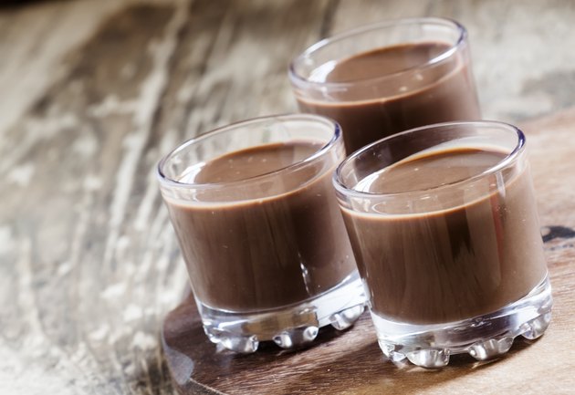 Liquid chocolate in a glass on the old wooden background