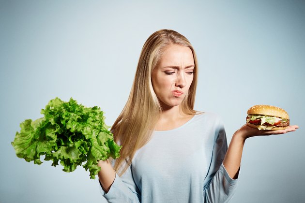 Pensive woman making decision between healthy food and fast food