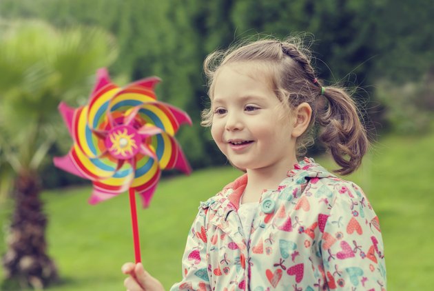 little cute girl playing with pinwheel in nature